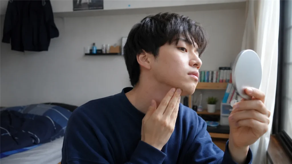 鏡で自分の顔まわりを確認する男子大学生