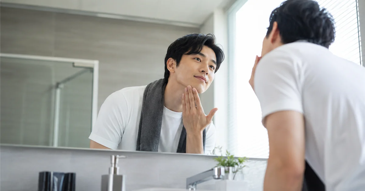 鏡で自分のあご周りを確認する身だしなみを整えた男性
